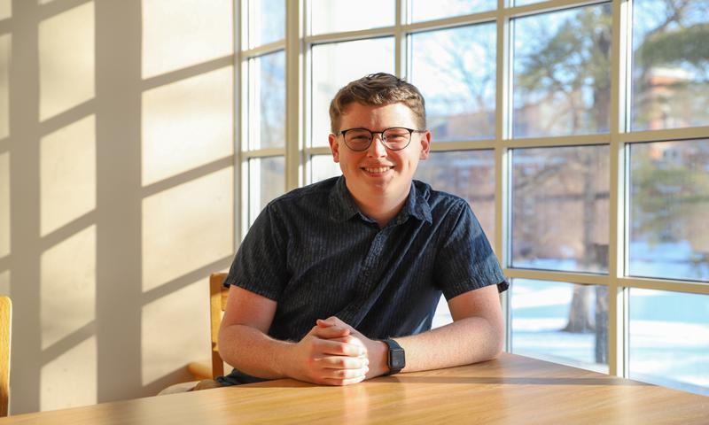 Brady Largent sits at a table in Lilly Library.